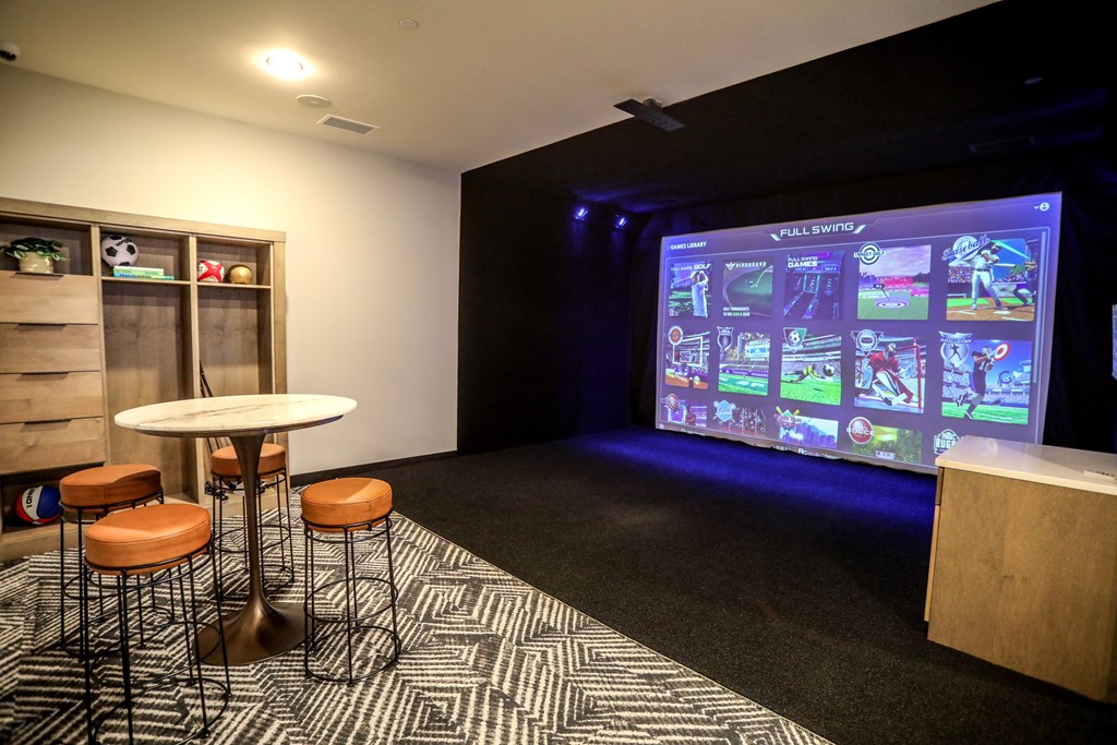 a room with a projector screen and tables and chairs