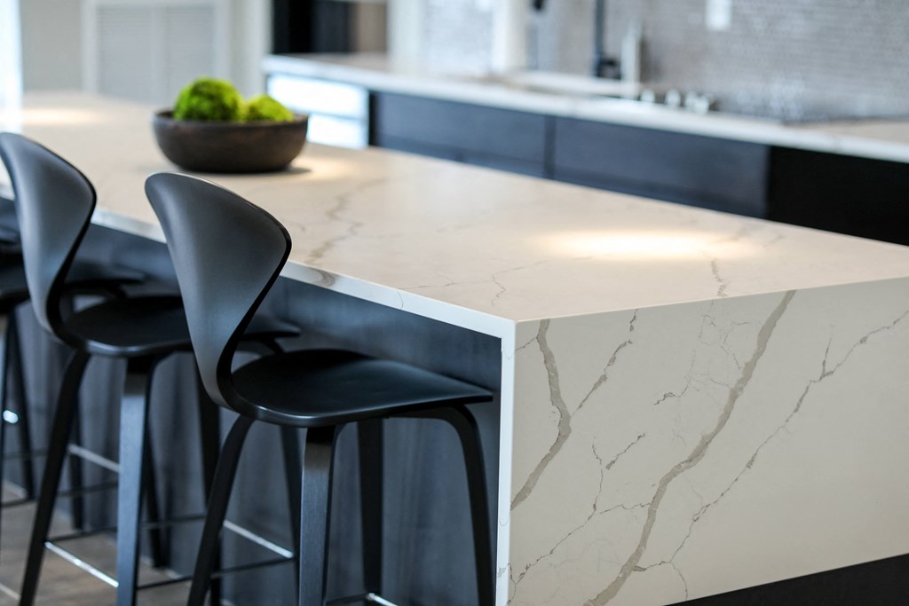 a kitchen with a marble counter top and black stools
