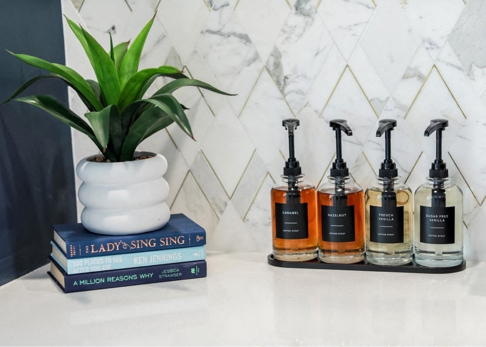 three bottles of hair styling products and a plant on a bathroom counter