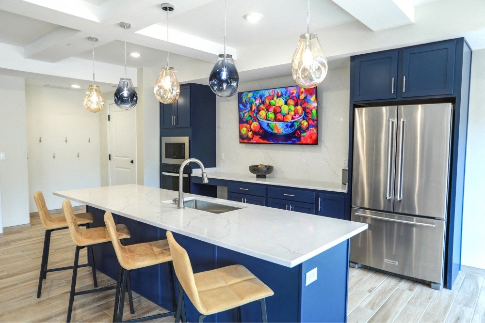 a kitchen with blue cabinets and a marble counter top and a stainless steel refrigerator