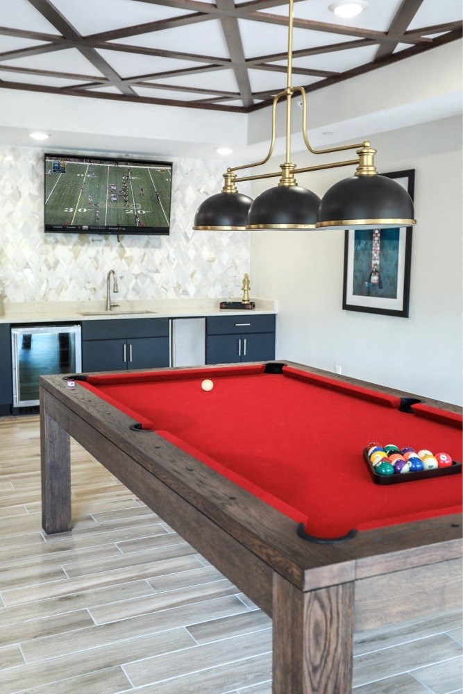 a red pool table in a game room with two lamps