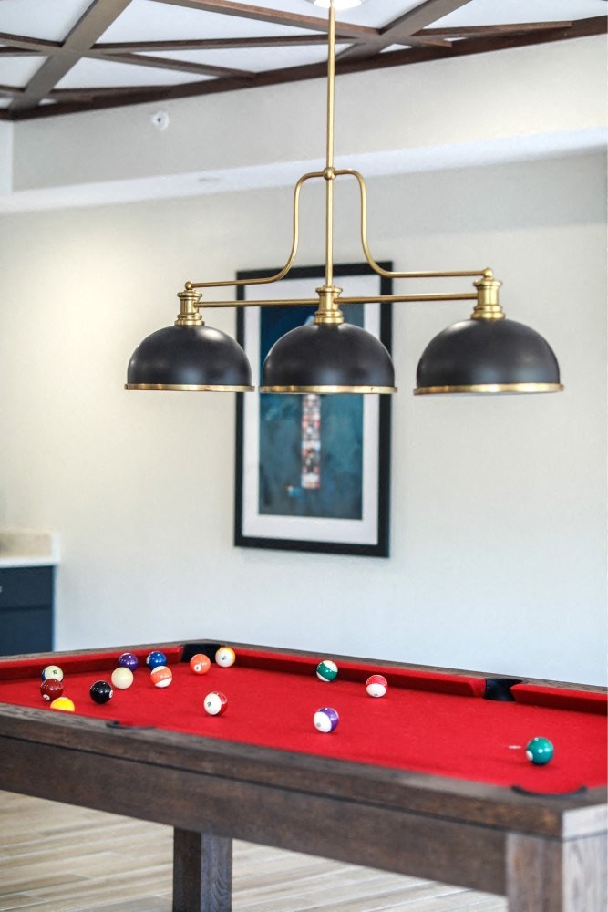 a row of pendants hanging over a pool table with a red and white blanket