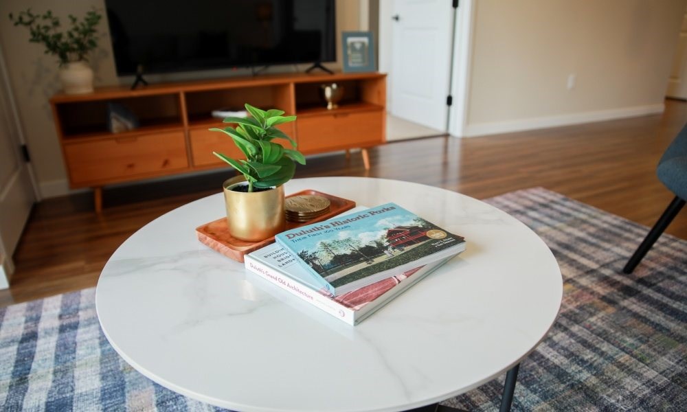 A small potted plant sits on a stack of books on a white table.