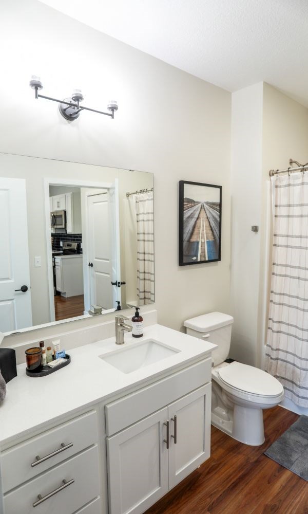 A white bathroom with a toilet, sink, and mirror.