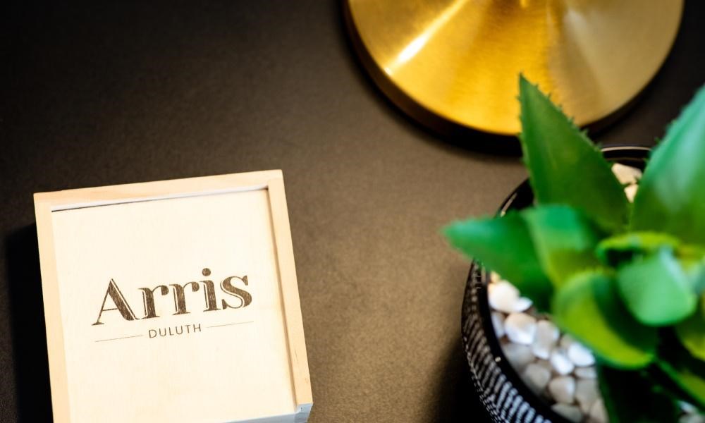 A box of Arris Duluth is placed on a table next to a plant.
