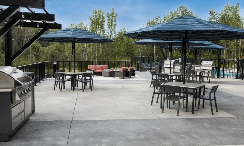 A patio with tables and chairs under umbrellas.