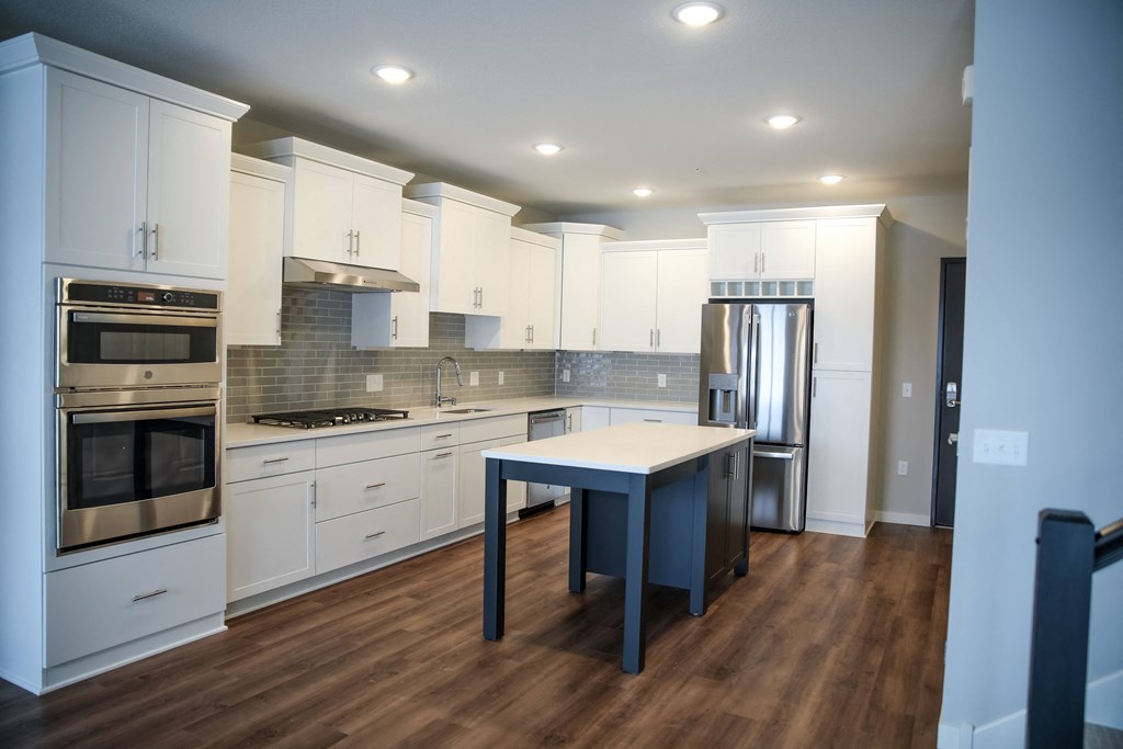 a kitchen with white cabinetry and a blue island in the middle of it