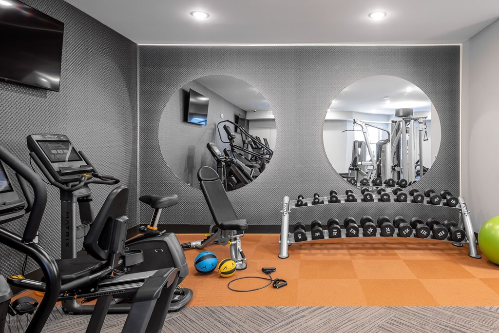 a gym with exercise equipment and round mirrors in the wall