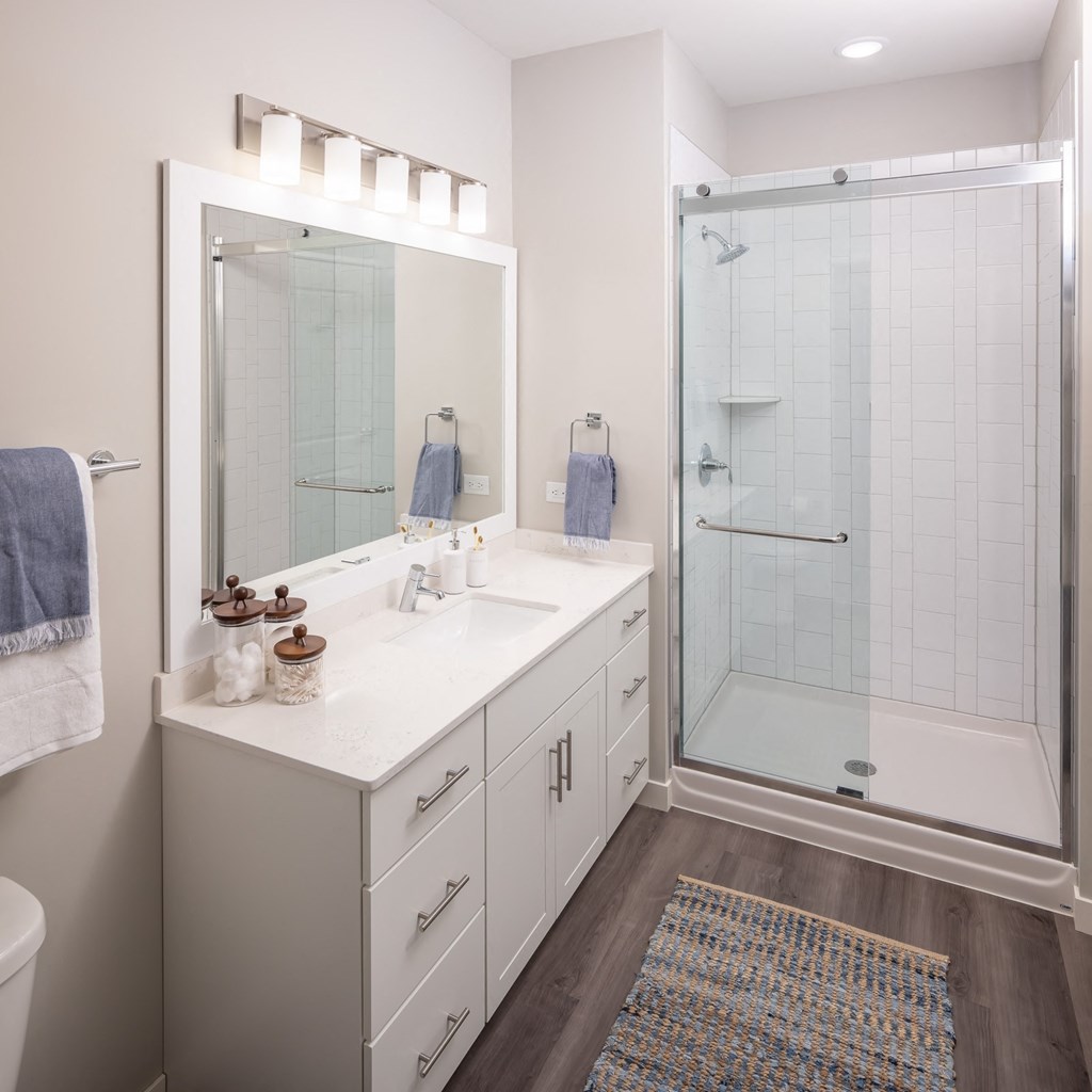 Large bathroom with white cabinets and walk-in shower