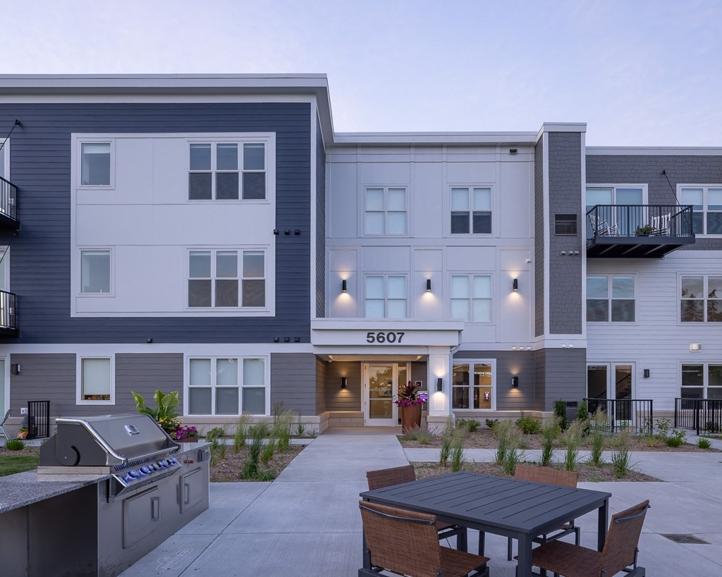 an exterior view of an apartment building with a patio and table