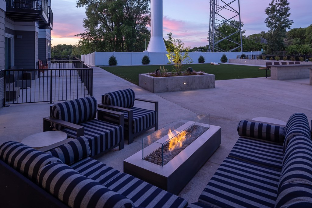 an outdoor lounge area with couches and a fire pit