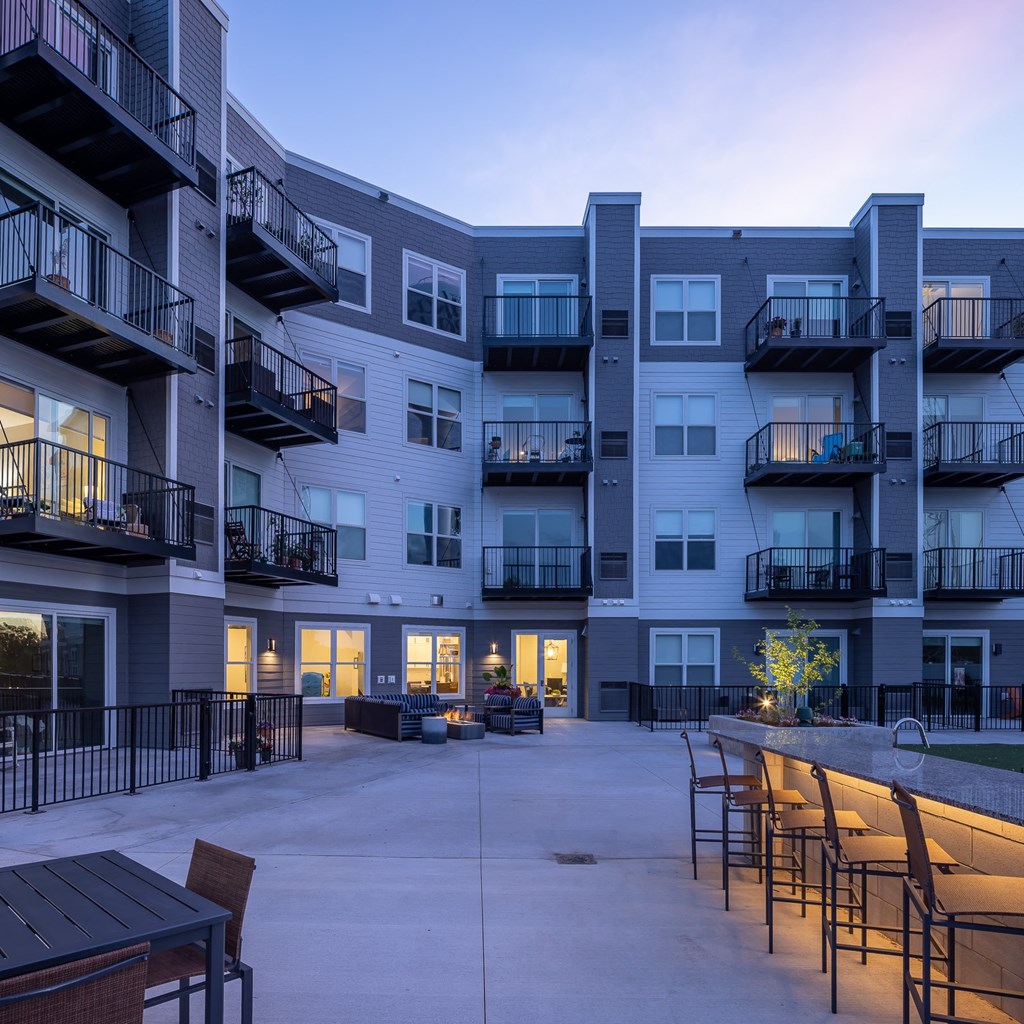an exterior view of an apartment building with a patio and tables