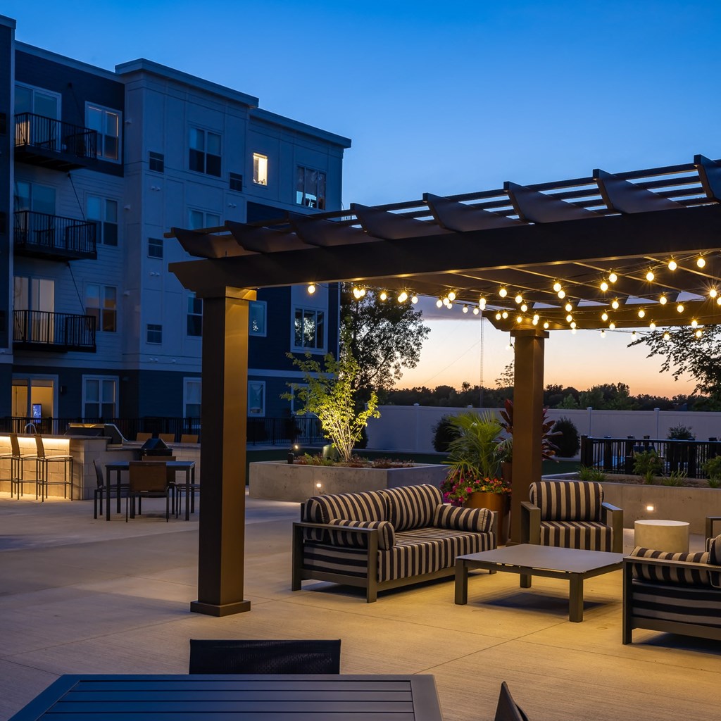 a patio with chairs and a pergola at night