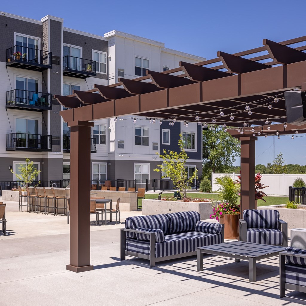 a patio with chairs and tables in front of an apartment building