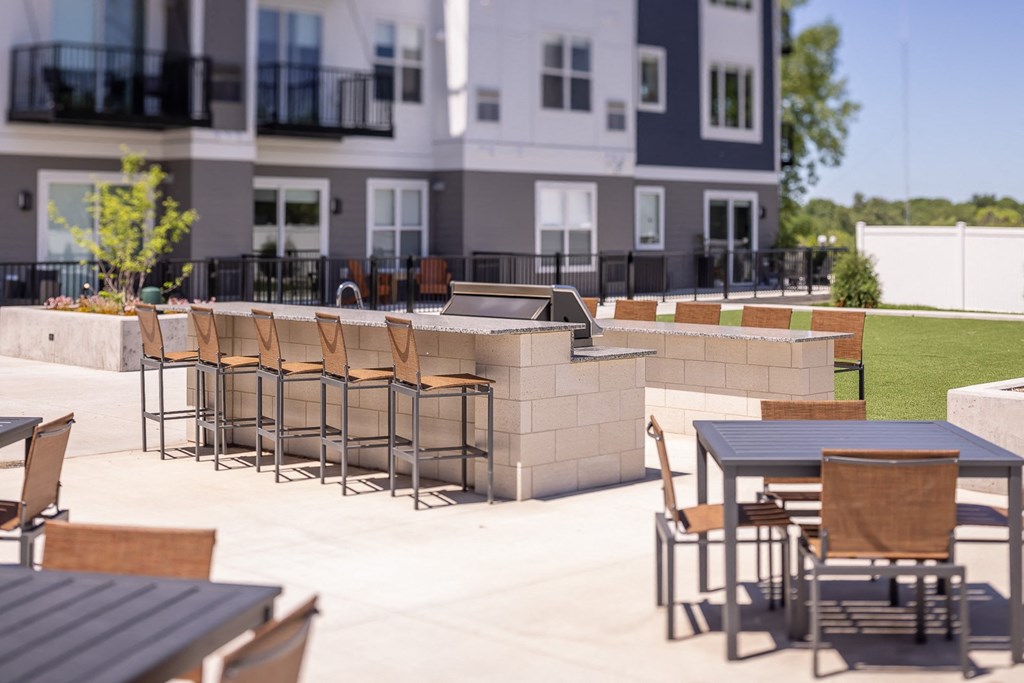 an outdoor patio with tables and chairs in front of an apartment building