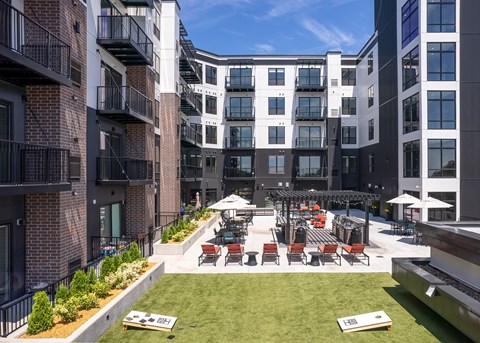 an outdoor area with lawn chairs and tables in front of an apartment building