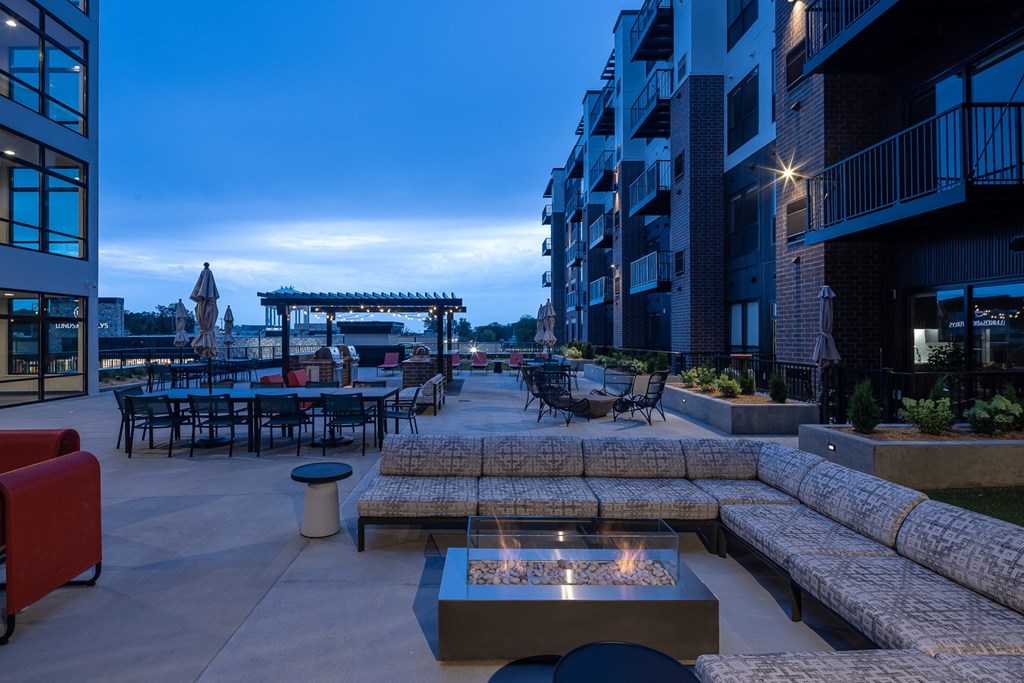 an outdoor patio with couches and tables and a fire pit