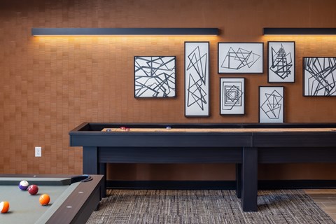 a game room with a pool table and artwork on the wall