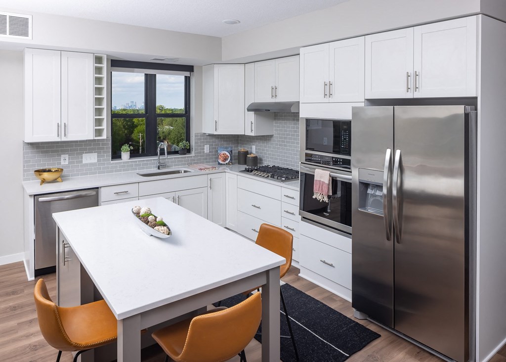 a kitchen with white cabinets and stainless steel appliances and a white table