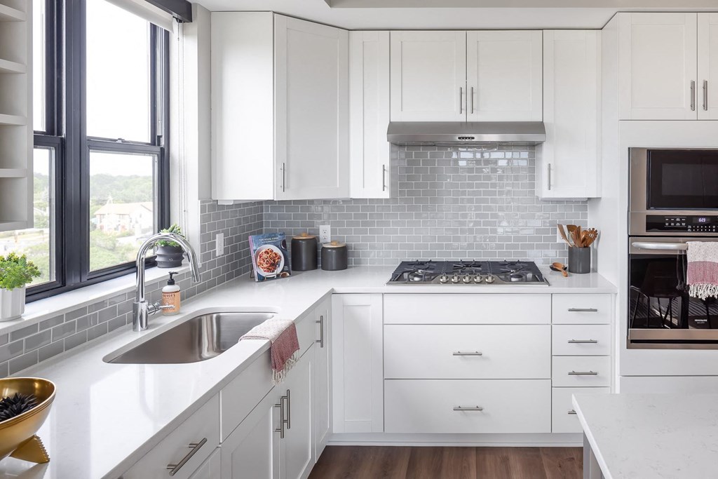 a white kitchen with a sink and a window
