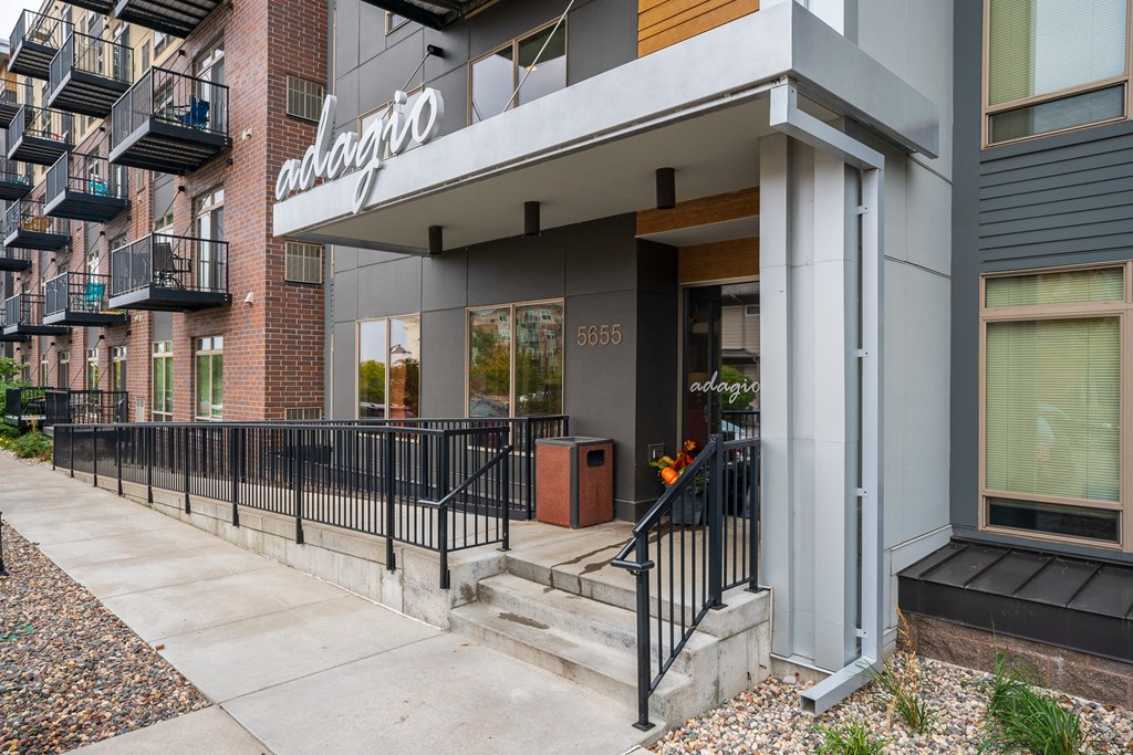 an apartment building with stairs and a sidewalk in front of it