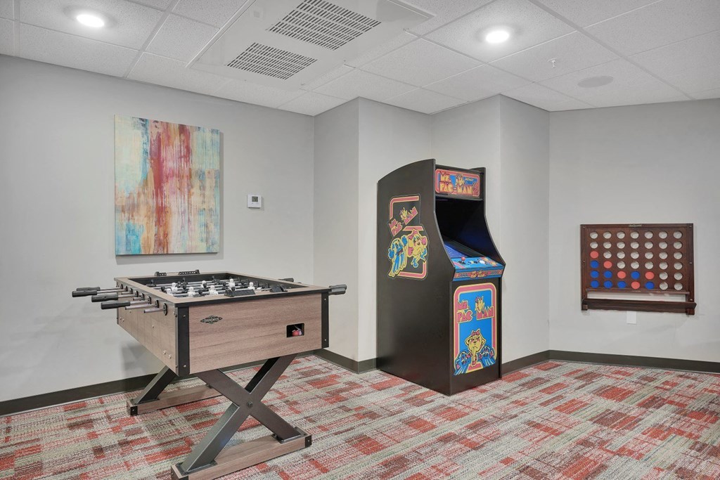 A room with a pool table, a pinball machine, and a painting on the wall.