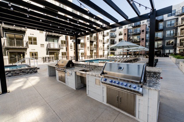 the outdoor kitchen is equipped with stainless steel appliances and granite counter tops