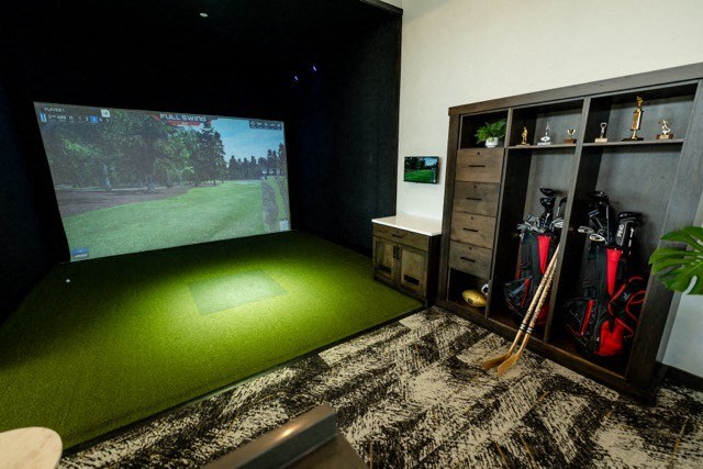 a living room with a golf simulator and a large screen tv