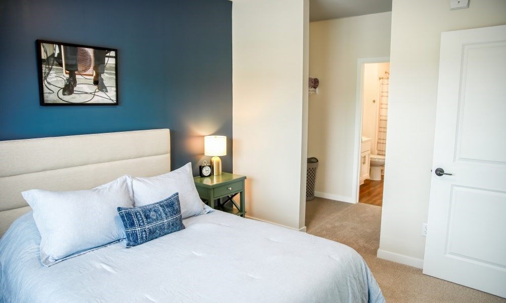 A bed with a white sheet and two pillows in a room with blue walls.