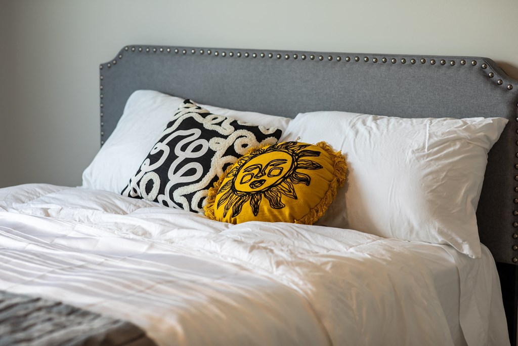 a bed with white pillows and a yellow pillow on it