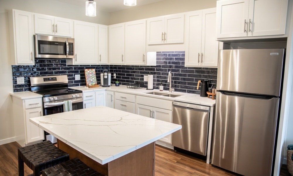 A kitchen with a white countertop and stainless steel appliances.
