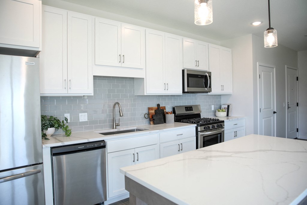 a large white kitchen with stainless steel appliances and white counter tops