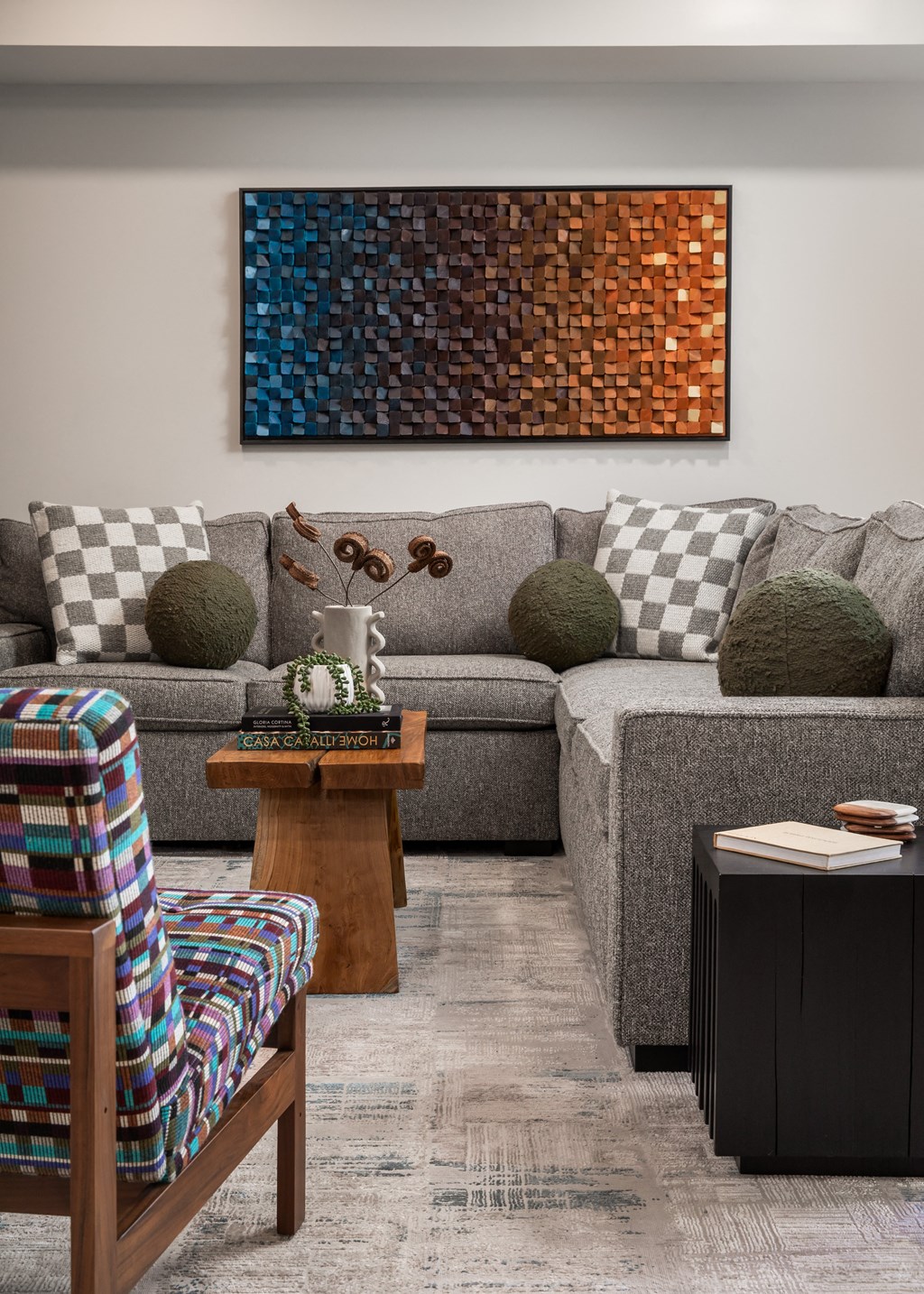 a living room with gray couches and a colorful painting on the wall