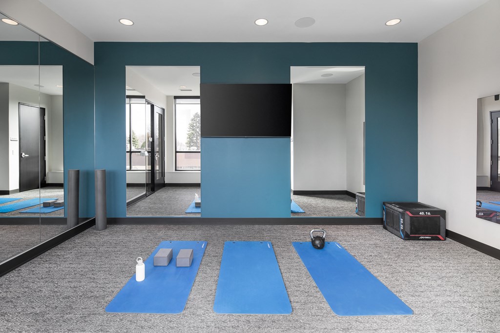a group of blue yoga mats in a room with mirrors and a suitcase