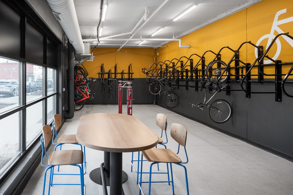 a bike room with tables and chairs and a wall with bikes on it