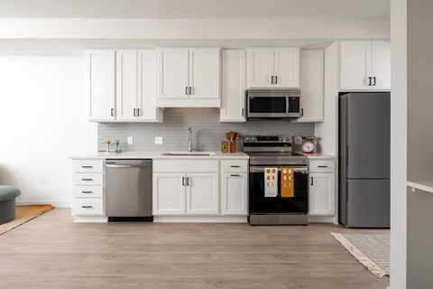 a white kitchen with stainless steel appliances and white cabinets