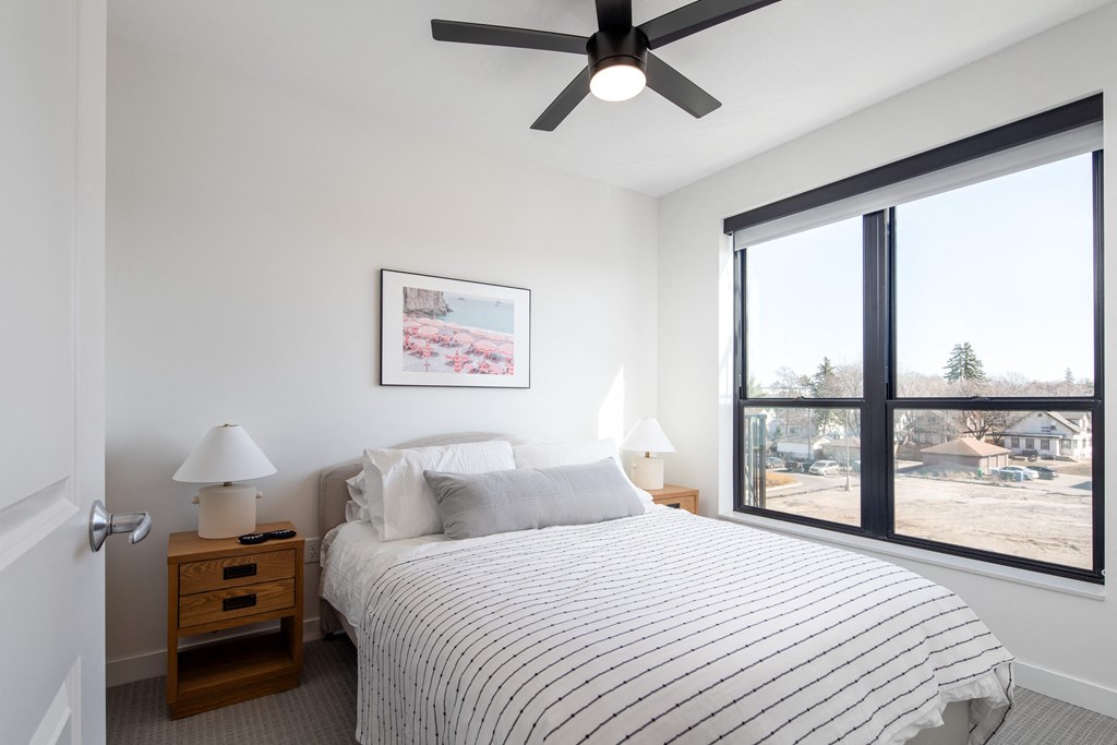 a bedroom with a bed and a ceiling fan and a large window
