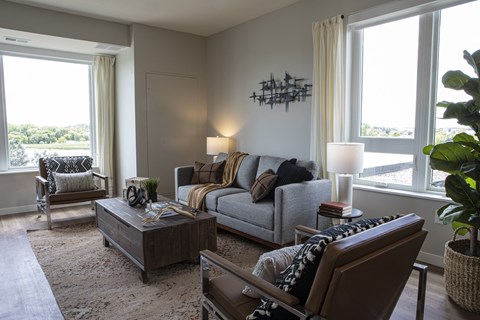 a living room with a gray couch and chairs and a large window