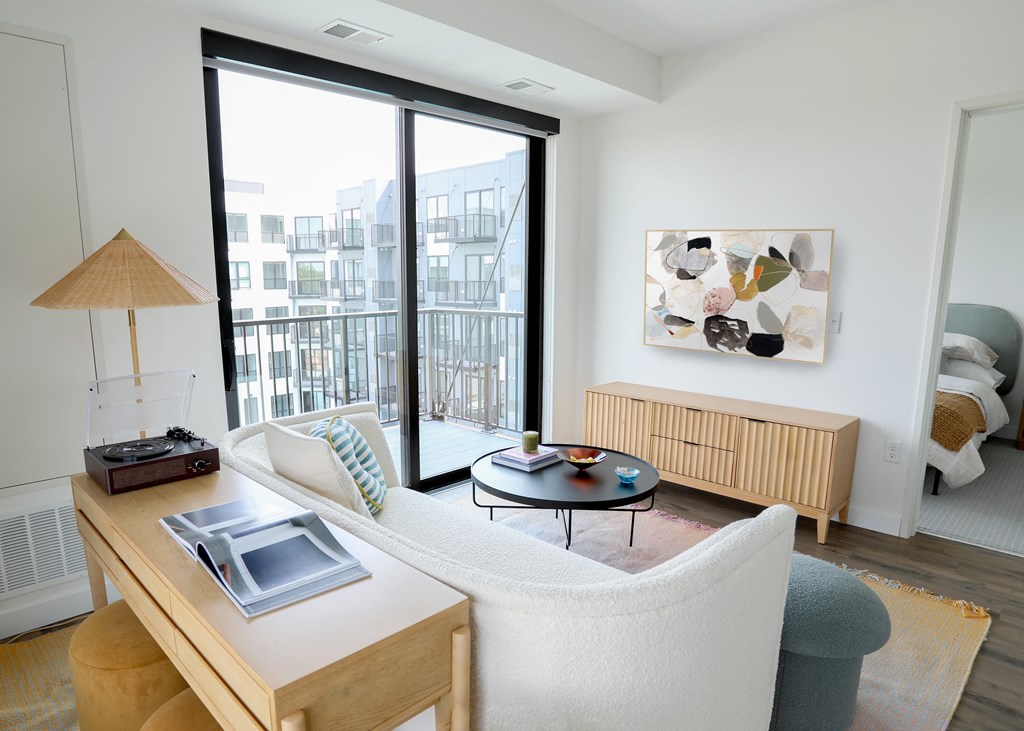 a living room with a white couch and a wooden table with a lamp on top of it