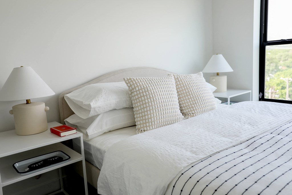 a bed with white sheets and pillows in a bedroom