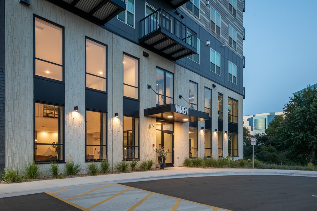 A modern building with a black and white facade and a parking lot in front.