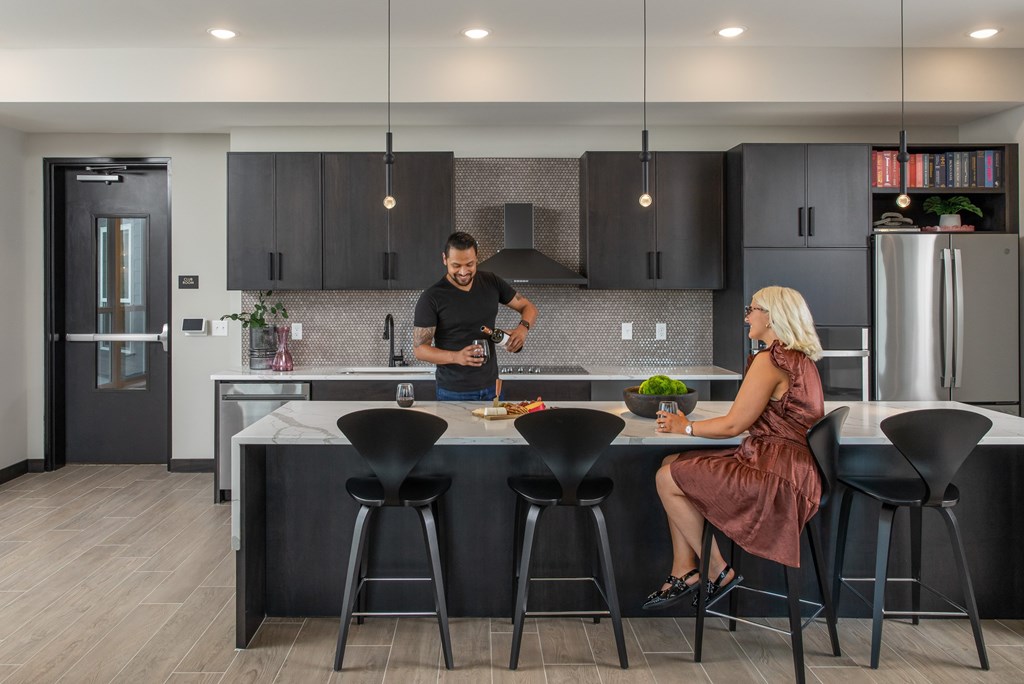 A man and woman are sitting at a kitchen island with black chairs.