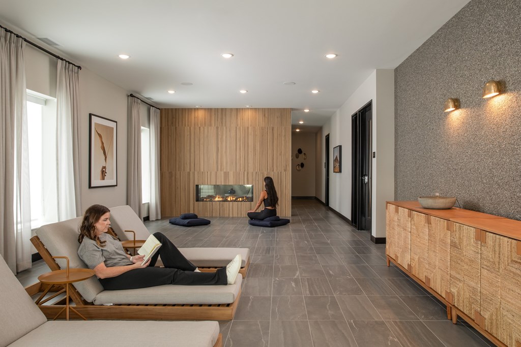 A woman is sitting on a chair in a room with a fireplace.