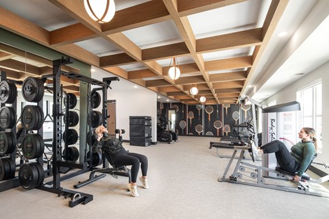 two women exercising in a gym with weights and machines
