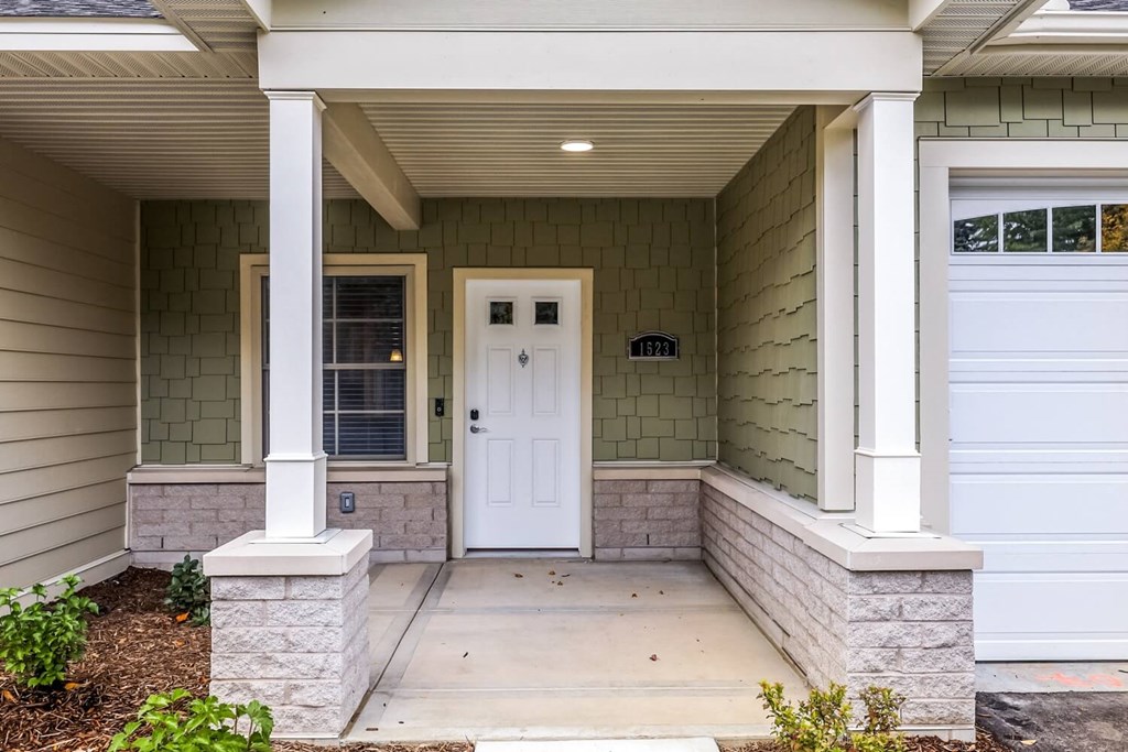 the front porch of a home with a white door