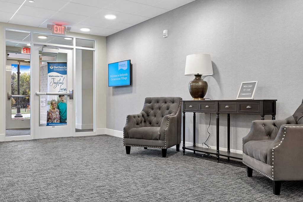 a waiting room with chairs and a table in front of a glass door