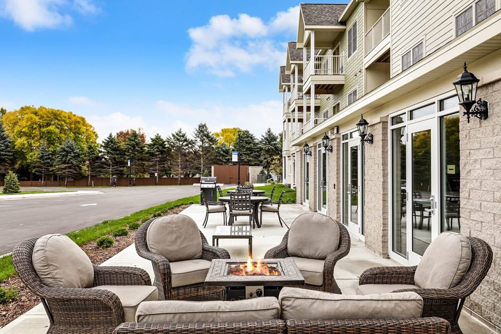 a patio with furniture and a fire pit in front of a house