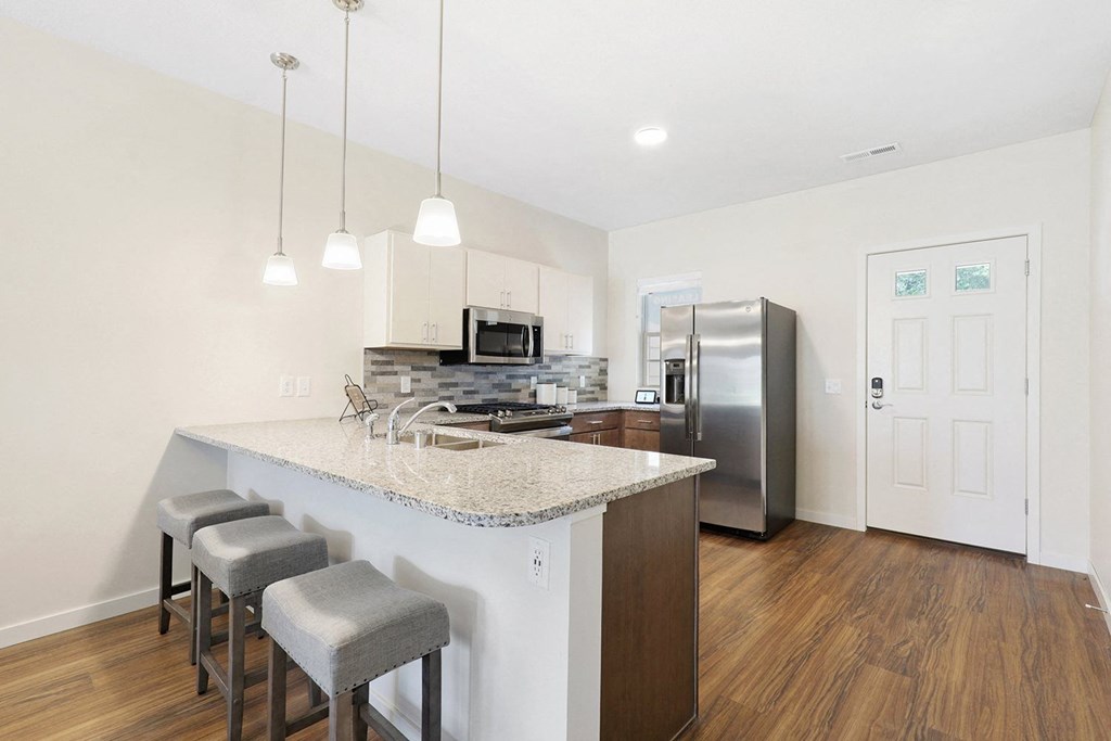 a kitchen with a marble counter top and a stainless steel refrigerator