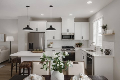 A modern kitchen with a dining table set for two.