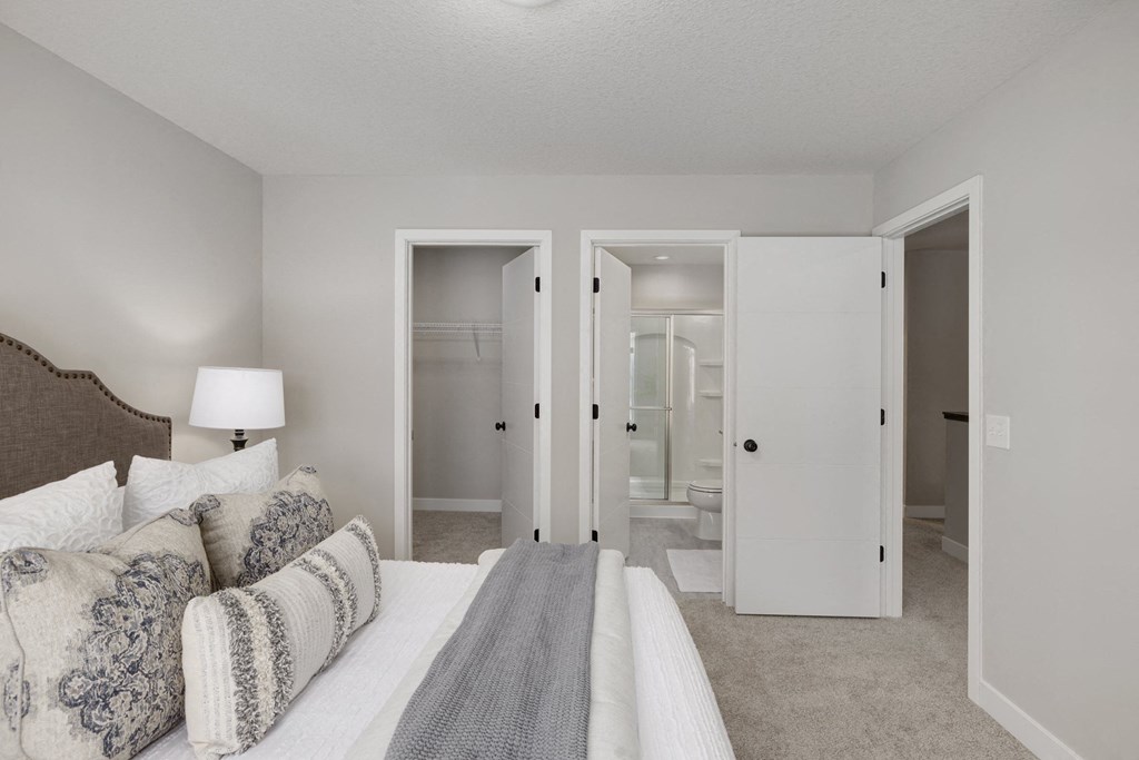 A bedroom with a bed, couch, and mirror.